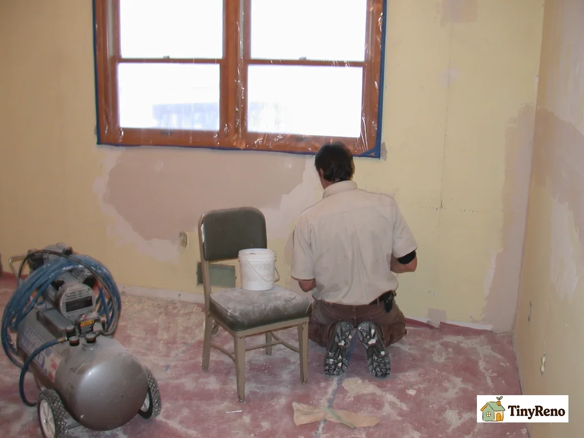 Hand applying joint compound to patch a small drywall hole